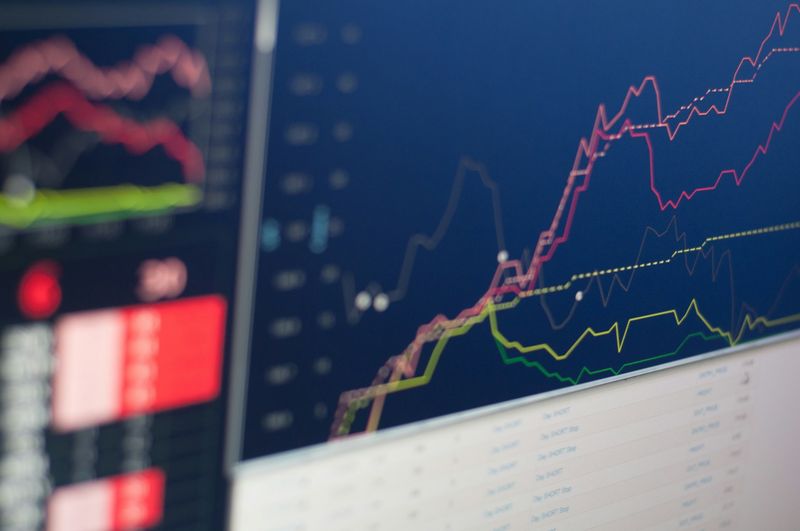 Close-up of a dark monitor showing colourful financial line charts trending upward — the kind of data bezant makes typed and programmable