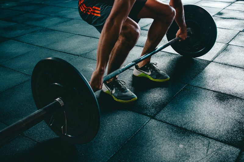 A loaded barbell resting on the floor of a dark gym