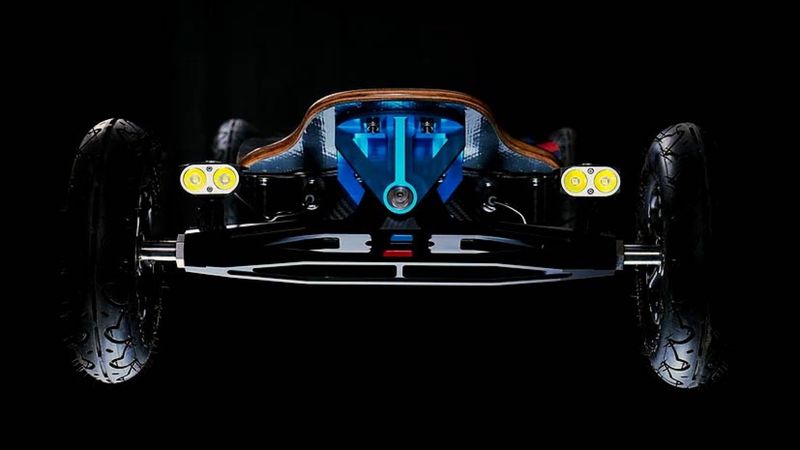 A LaCroix electric skateboard shot head-on against black — Hypertrucks splayed wide on pneumatic tyres, a blue anodised hanger, twin LED pods and a carbon deck.
